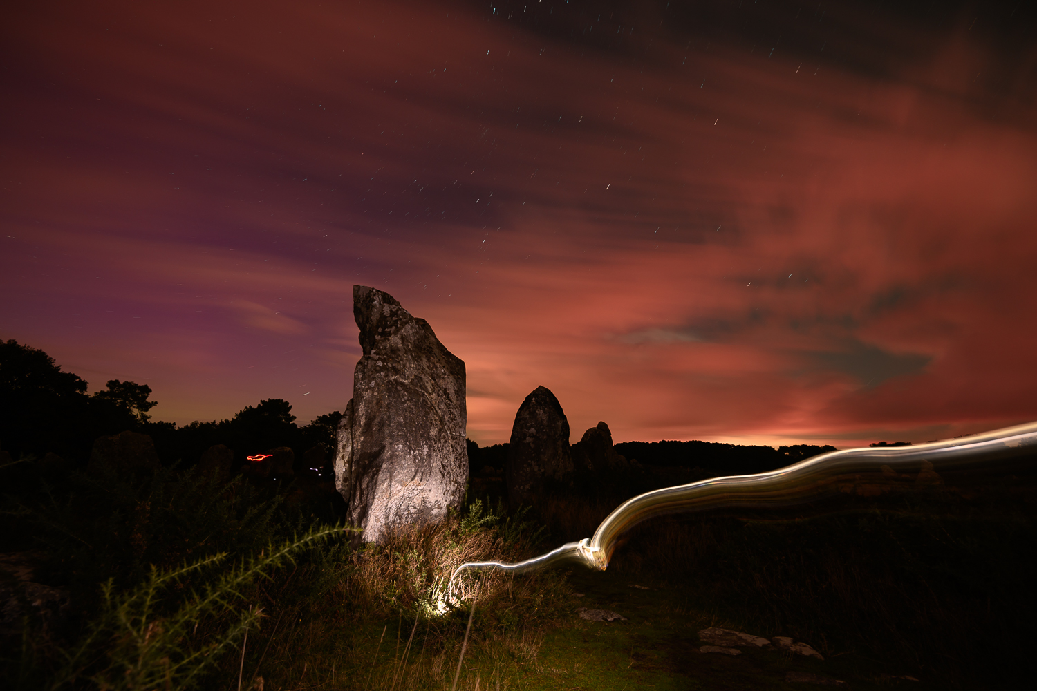Aurore boréale rouge au-dessus des menhirs des alignements de Carnac, avec light painting — photographie de Franck Besrest
